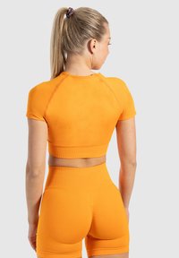  Oranje sportieve crop top met korte mouwen en geribbelde onderkant, gecombineerd met bijpassende hoge shorts. Glad materiaal.