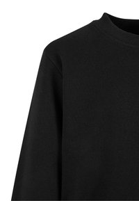 Sudadera negra con cuello acanalado, mangas largas y una superficie de tela texturizada. El diseño es simple y sin adornos.