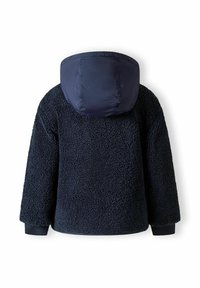 Marineblauwe fleecejack met een gestructureerd, pluizig oppervlak en een effen marineblauwe capuchon. Voorzien van lange mouwen en elastische manchetten.