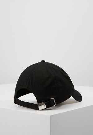 Sort bomuld baseballkasket med justerbar strop og metalspænde, placeret på en hvid overflade mod en ensartet lys baggrund.