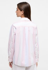 White shirt with vertical red and blue stripes, long sleeves, and a pointed collar. Features a back pleat and buttoned cuffs.