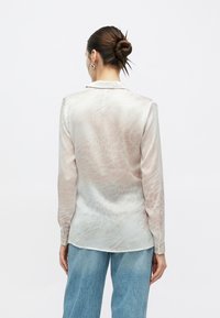 Μεταξωτό πο υκάμισο με διακριτικό αφηρημένο σχέδιο σε ανοιχτό ροζ και εκρού αποχρώσεις. Διαθέτει γιακά και μανσέτες με κουμπιά, εμφανισμένο από πίσω.