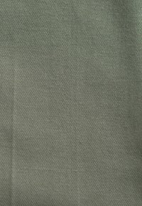 Material texturat de culoare verde, cu un model uniform de țesătură și linii diagonale subtile. Materialul pare durabil și are o finisare mată.