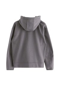 Hoodie harmaa, jossa on rento leikkaus, sileä pinta ja näkyvät ompeluyksityiskohdat. Varustettu pitkillä hihoilla ja puolipitkällä leikkauksella.