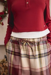 Red long-sleeve pullover with a front button and white underlayer, paired with checkered plaid lounge pants featuring a drawstring waist.