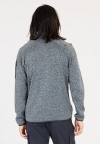 Grå sweater med et struktureret strikkemønster, der har høj krave og lange ærmer. Inkluderer et logo detaljeret på skulderen og ribbet manchetter.