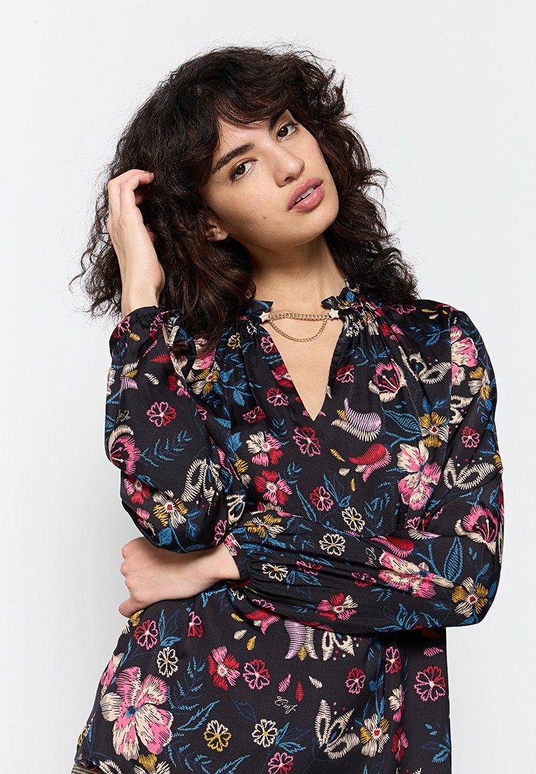 Blusa nera floreale con ricami multicolore, maniche a sbuffo, scollatura a V e dettagli arricciati attorno alla scollatura.