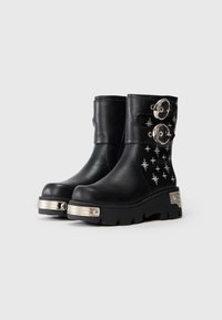Botas de cuero negro hasta la pantorrilla con bordado de estrellas plateadas, dos hebillas plateadas y suelas gruesas con acentos de metal en la punta y el tacón.