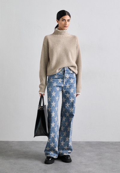 Beige gerippter Rollkragenpullover, hellblaue Jeans mit Sternmuster und weitem Bein, schwarze Tragetasche und klobige schwarze Schuhe. Minimalistisches Design.