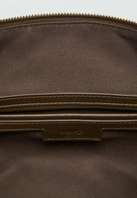 Hnedý plátenný vak s vnútorným zipsovým vreckom a koženým štítkom s nápisom "MNG". Hladká textúra a jednoduchý dizajn.