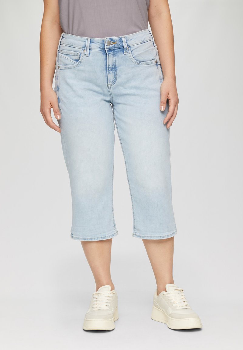 Pantalons capri en denim bleu clair avec une coupe droite, présentant des poches avant, une fermeture à bouton et un délavage légèrement usé. Associés à des baskets blanches.