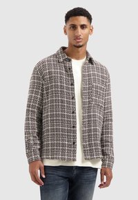 Knoopshirts in een gestructureerde bruine en witte stof, met een relaxte pasvorm, een kraag en zichtbare knopen aan de voorkant.