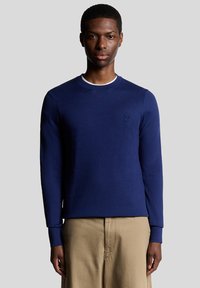 Maglietta a maniche lunghe blu navy con scollo rotondo e dettaglio discreto del logo sul petto; tessuto a maglia liscia e design aderente.