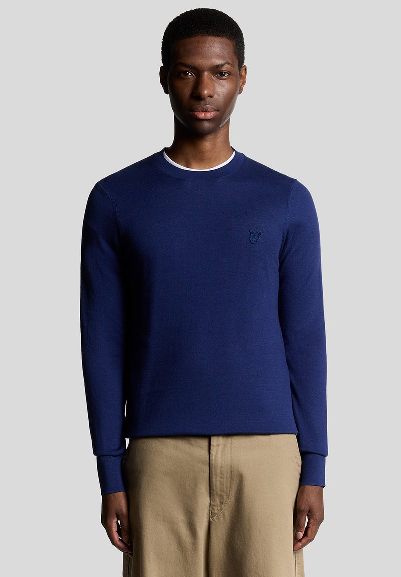 Maglietta a maniche lunghe blu navy con scollo rotondo e dettaglio discreto del logo sul petto; tessuto a maglia liscia e design aderente.