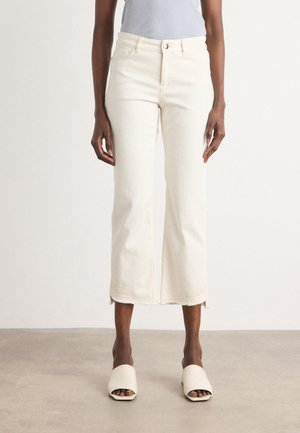 Beige cropped jeans met een ruwe zoom, gemaakt van denimstof. Gecombineerd met lichtgekleurde schuifsandalen. Vlakke voorzakken en sluiting met knoop.