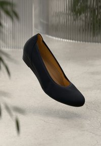Scarpa da balletto nera, piatta, con esterno liscio e punta rotonda. Interno morbido con imbottitura e un leggero tacco per il comfort.