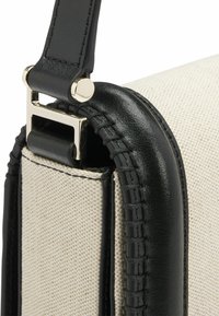 Borsa in tela con dettagli in pelle nera, caratterizzata da una forma strutturata, una superficie testurizzata e finiture in metallo dorato.