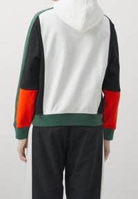 Felpa con cappuccio caratterizzata da un design a blocchi di colore con pannelli bianchi, neri, verdi e rossi; tessuto morbido con polsini e orlo a coste.