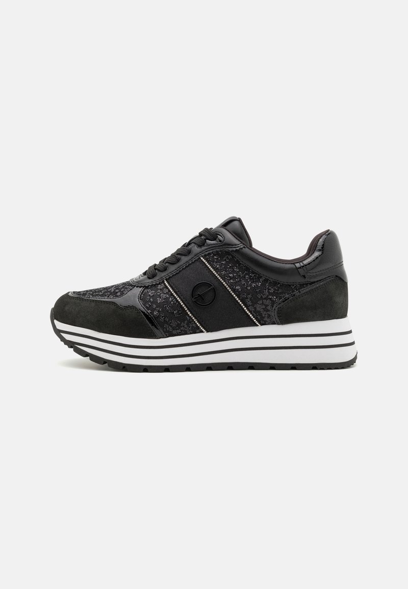 Black sneaker with black laces, suede and textured fabric panels, white and black striped sole, and a circular logo on the side.