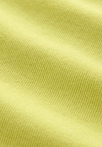Lichtgroene zachte gebreide stof met een gladde textuur en een fijn, consistent ribbelpatroon, dat in golven soepel valt.