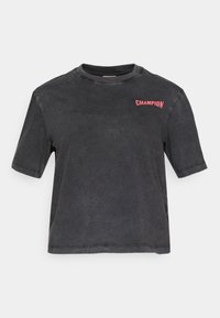 Sort kortærmet t-shirt lavet af blød bomuld, med en falmet tekstur og et lille pink "CHAMPION" logo på den øverste venstre side.