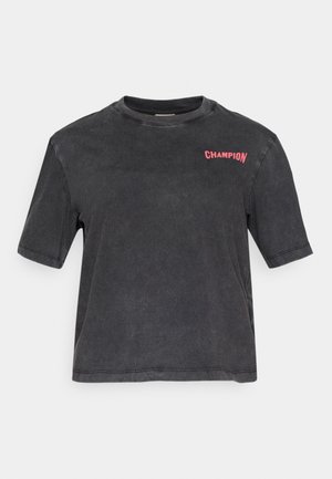 Czarna, krótki rękaw t-shirt wykonany z miękkiej bawełny, z wyblakłą teksturą i małym różowym logo "CHAMPION" na górnej lewej stronie.