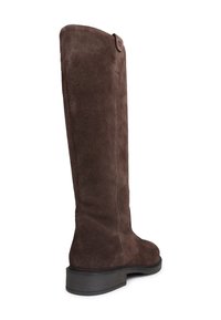 Botte en daim marron au-dessus du genou, avec un bout rond, un petit talon empilé, et une couture courant à l'arrière, avec un simple accent sur le haut.