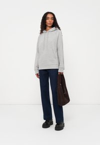 Grijze hoodie, relaxte pasvorm, gecombineerd met donkerblauwe wijde broek en een bruine handtas. Zachte textuur en casual ontwerp.