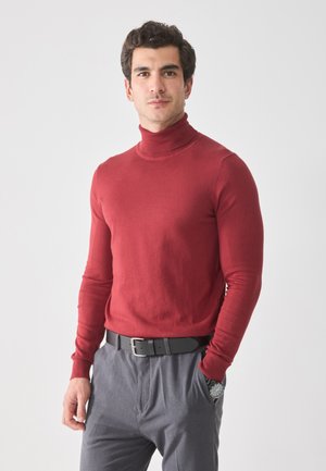 Roter Rollkragenpullover aus glattem Strickmaterial, taillierte Passform, lange Ärmel, kombiniert mit grauen Hosen und einem schwarzen Gürtel.
