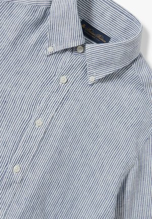 Camicia a righe blu e bianca. Presenta un colletto alla francese, bottoni perlati e un tessuto di cotone testurizzato.
