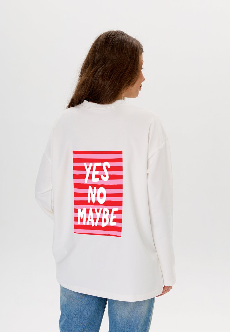 Witte oversized sweatshirt met een rood en roze gestreepte achterkant en de woorden "JA NEE MISSCHIEN" in vetgedrukte witte letters.