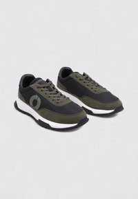 Zapatillas en materiales negro y verde oscuro, con una parte superior texturizada, cierre con cordones, suela acolchada y un acento blanco en la entresuela.