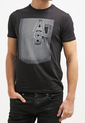 Černé tričko s krátkým rukávem, který má bílý pruhovaný grafický design s textem "AUST" uprostřed, vyrobené z měkké, lehké tkaniny.