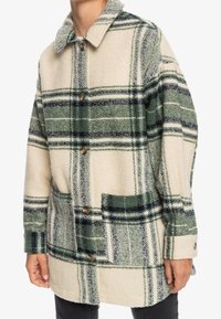 Abrigo de mezcla de lana con estampado de cuadros en verde y crema, grandes bolsillos delanteros, cierre de botones y diseño clásico de cuello.