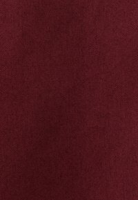 Tessuto bordeaux con una superficie liscia e un motivo a righe diagonali, adatto per applicazioni di tappezzeria o abbigliamento.