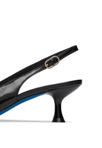 Scarpa slingback in vernice nera con una finitura lucida, punta arrotondata e una suola blu distintiva. Presenta un accentuato filo dorato.