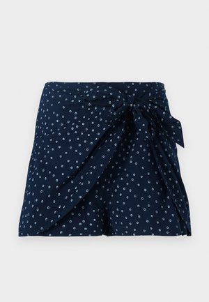 Dunkelblaue Shorts mit einem Wickeldesign und vorderem Bindedetail. Besitzt ein verstreutes kreisförmiges weißes Muster. Hergestellt aus leichtem Stoff.