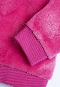 Polarowy sweatshirt w intensywnym różowym kolorze, charakteryzujący się miękką fakturą. Rękawy ściągacze w nieco ciemniejszym odcieniu różu, z gładkim i puszystym kontrastem materiału.