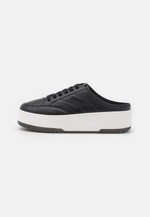 Czarny skórzany sneaker typu slip-on z wiązaniami z przodu i grubą białą podeszwą platformową, pokazany z profilu na białym tle.