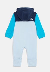 Kapa v zeleni in turkizni barvi za dojenčke s temno modrimi rameni in logotipom The North Face na hrbtu.
