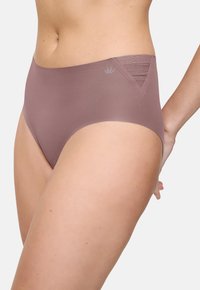 Femeie purtând lenjerie intimă mauve cu talie înaltă, fără cusături, cu detalii din plasă triunghiulară texturată pe șold și un mic logo în formă de coroană.