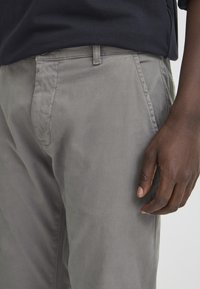 Light gray, cotton trousers with a smooth texture, featuring front pockets, a slim fit, and a flat front design. Casual style.