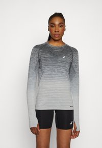 Langærmet grå gradient træningsbluse med tekstureret mønster, rund hals, og tommelhuller, parret med sorte shorts.