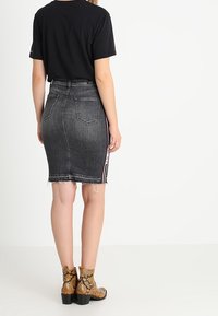 Černé tričko, šedá džínsová tužková sukně s třepeným lemem a pruhovaným detailem. Hnědé kotníkové boty s hadím vzorem a blokovými podpatky.