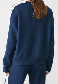 Sweatshirt blu navy in morbido tessuto con colletto rotondo, maniche lunghe e polsini a costine, con un dettaglio di cucitura sulla schiena.