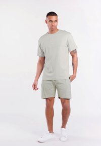 Lichtgrijs t-shirt met een ronde halslijn en logo, gecombineerd met bijpassende shorts. Beide zijn gemaakt van zachte, ademende stof, ideaal voor casual kleding.
