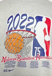 Logo du 75e anniversaire de la NBA 2022 avec un ballon de basketball passant à travers un cerceau et la liste de toutes les équipes NBA en couleurs rouge, bleu, orange et blanc.