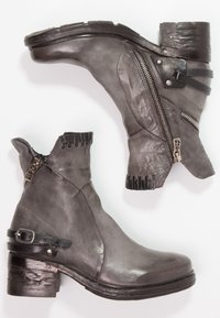 Graue Lederstiefeletten mit einem klobigen Absatz, Seiteneingriff, dekorativen schwarzen Akzenten und einer strukturierten Oberseite mit Ausschnitten.