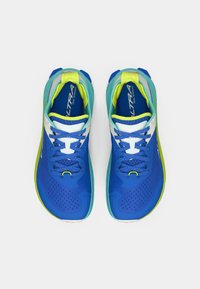 Baskets de trail de course bleues avec une surface texturée, des accents verts et une semelle intermédiaire blanche. Présentent un système de laçage et un col rembourré.