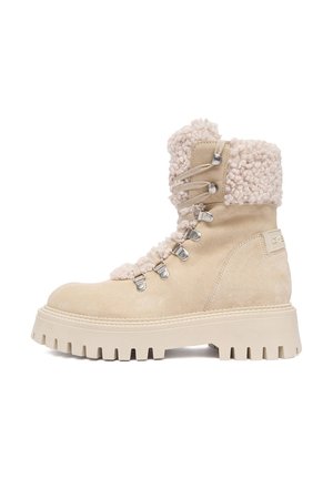 Beige suede winter boot with thick rubber sole, metal eyelets, lace-up front, and plush shearling collar and tongue lining.